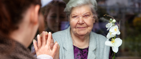 Older woman with her hand to a window