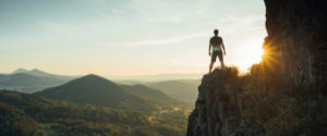 man on cliff looking out at mountains